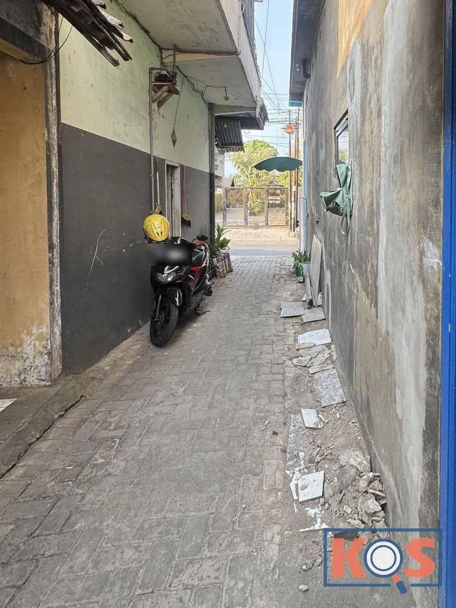 Gang beraspal paving di depan rumah, dengan motor terparkir