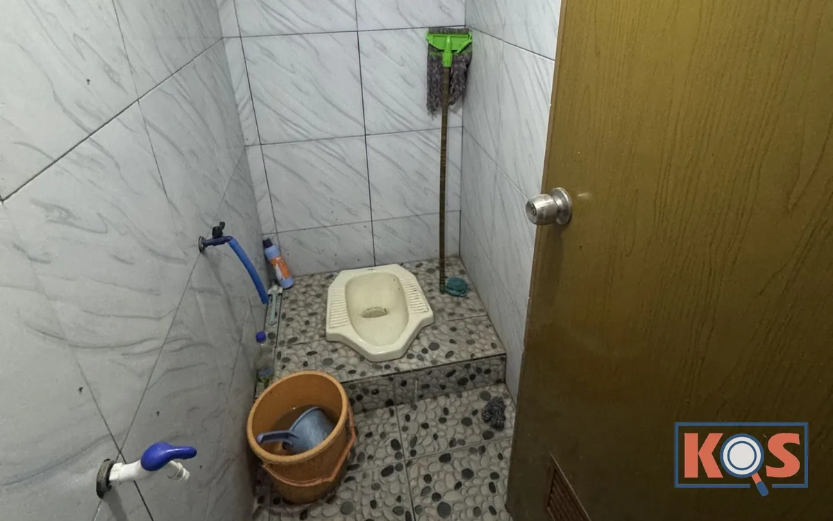 Kamar mandi dengan kloset jongkok, ember, dan keran